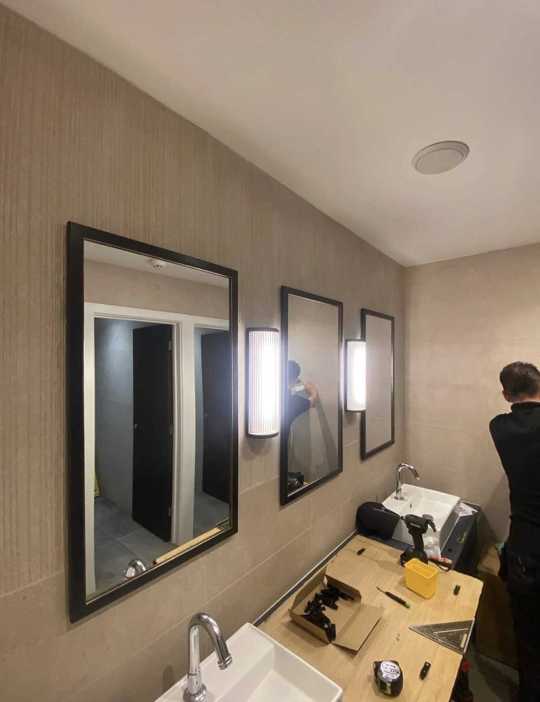 Wall lights and mirrors being installed during a washroom refurbishment